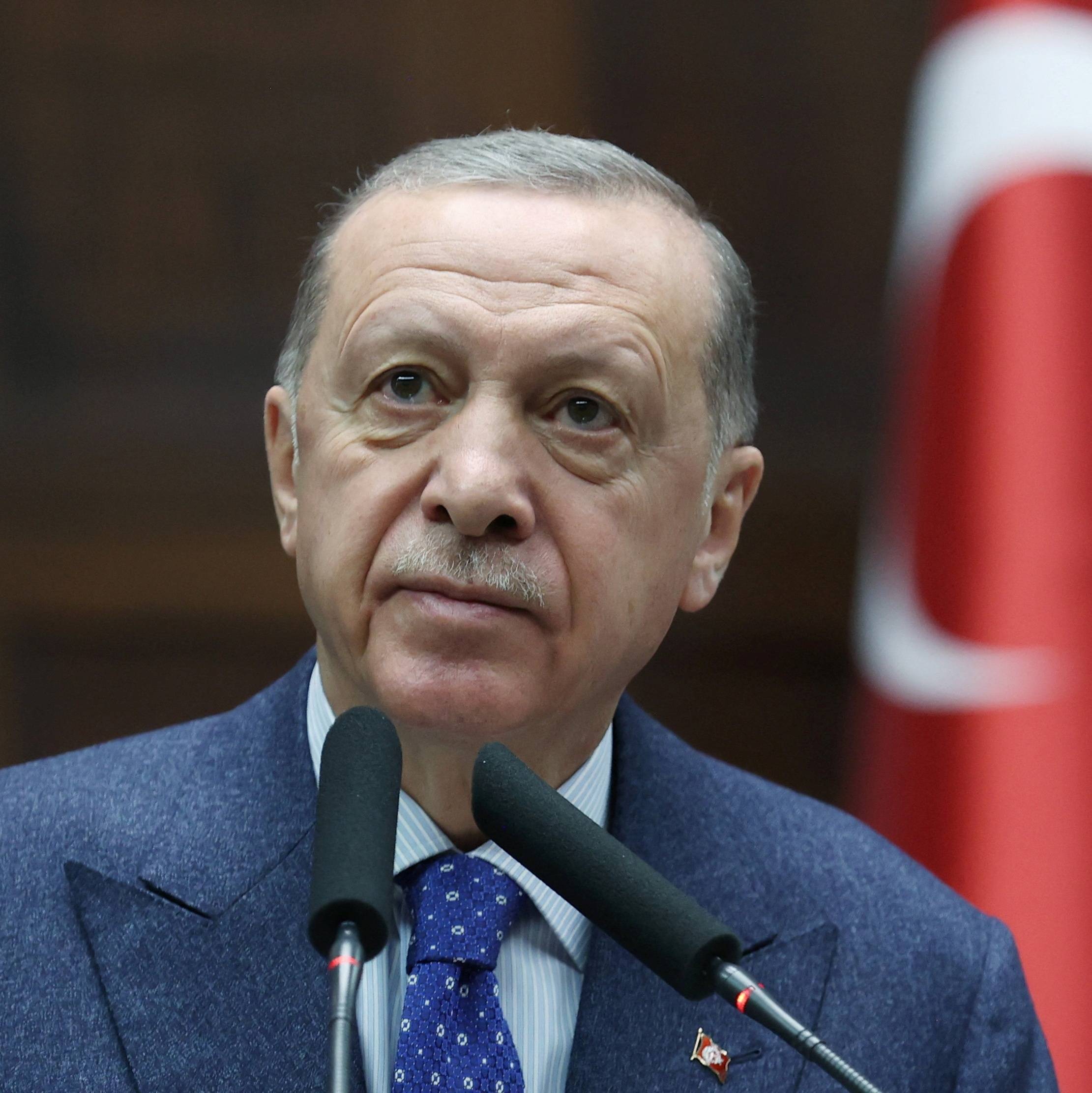 Recep Tayyip Erdogan discursando, com a bandeira da Turquia ao fundo, enquanto busca ampliar o poder turco na Síria