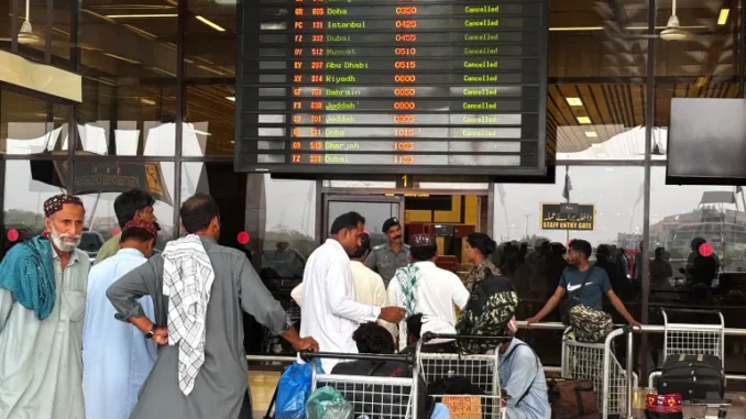 Passageiros aguardam no Aeroporto Internacional de Jinnah após cancelamentos de voos em Karachi.