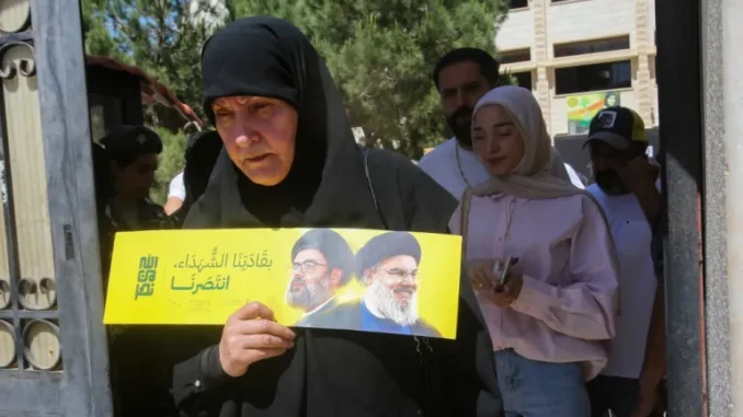 Mulher segura folheto com retratos de líderes do Hezbollah em seção eleitoral em Nabatieh, no sul do Líbano, durante as eleições municipais de maio de 2025.