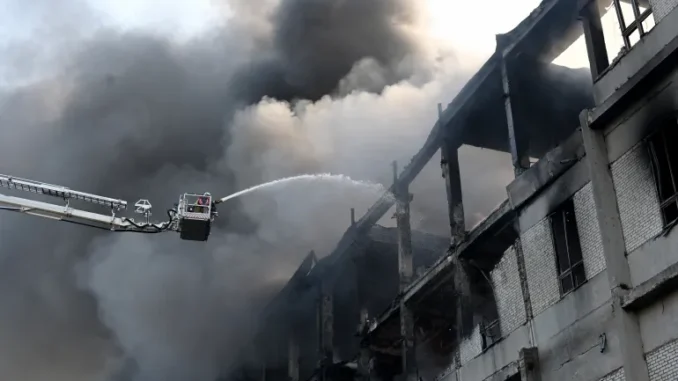Bombeiro apagando incêndio em planta civil após ataques russos em Kharkiv