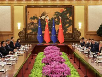 Reunião oficial da 25ª Cúpula China-União Europeia em Pequim com delegações chinesa e europeia sentadas em lados opostos de uma mesa longa, bandeiras da China e da UE ao fundo.