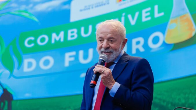 Presidente Lula discursa com microfone em evento sobre políticas energéticas, diante de painel com os dizeres "Combustível do Futuro".