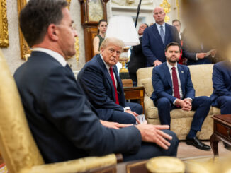 Foto de Donald Trump e outros políticos em uma reunião formal, com Trump sentado no centro olhando seriamente para um interlocutor.