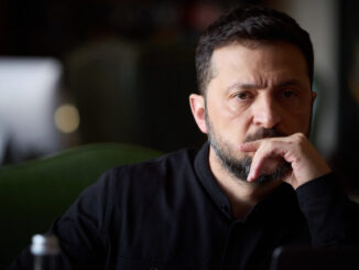 Retrato do presidente ucraniano Volodymyr Zelensky, com expressão pensativa, vestindo camisa preta, em ambiente com iluminação suave e fundo desfocado.