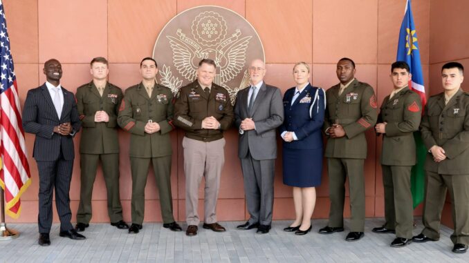 Militares e representantes civis do AFRICOM posam para foto oficial em frente a símbolo dos EUA, com bandeiras dos Estados Unidos e Namíbia ao fundo.
