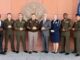 Militares e representantes civis do AFRICOM posam para foto oficial em frente a símbolo dos EUA, com bandeiras dos Estados Unidos e Namíbia ao fundo.