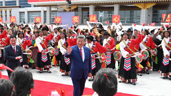 Xi Jinping acenando durante apresentação cultural em Tianjin, com grupo de artistas em trajes tradicionais comemorando a cúpula da OCX.
