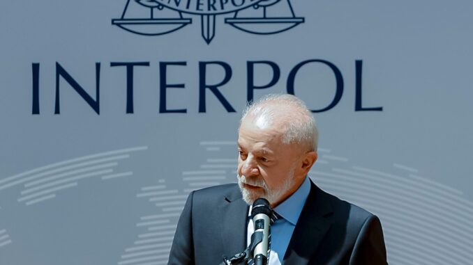 Presidente Luiz Inácio Lula da Silva discursando na sede da Interpol, França, com destaque para expressão facial e gestos durante o discurso.