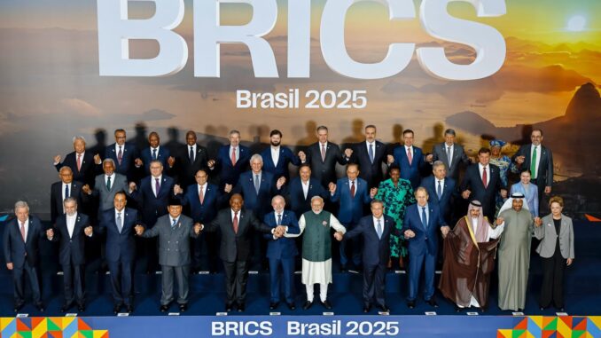 Foto oficial da Cúpula dos BRICS Brasil 2025, mostrando líderes e representantes dos países membros, convidados e organizações internacionais, reunidos em pose oficial e de mãos dadas, com o cenário do pôr do sol e a logo “BRICS Brasil 2025” ao fundo.