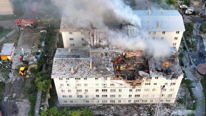 Edifício residencial danificado e em chamas após ataque aéreo russo em agosto de 2025, com bombeiros no local.