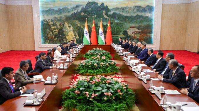 Líderes da Índia e da China em reunião bilateral com suas respectivas delegações, com bandeiras nacionais ao fundo, discutindo cooperação estratégica e relações diplomáticas.