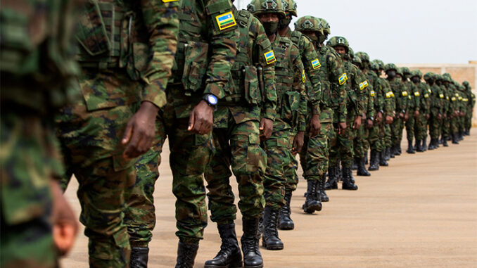 Soldados das Forças de Defesa de Ruanda alinhados em formação, usando uniformes camuflados com distintivos amarelos e azuis.