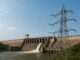 Usina hidrelétrica de Mphanda Nkuwa em Moçambique com torre de transmissão elétrica em primeiro plano, mostrando a geração de energia hidroelétrica.
