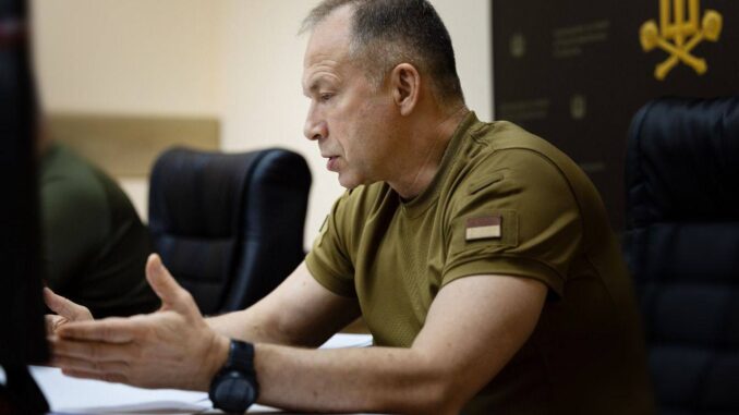 Oleksandr Syrskyi, chefe do Estado-Maior das Forças Armadas da Ucrânia, em reunião de análise das operações militares de agosto de 2025, falando e gesticulando, sentado à mesa com documentos.