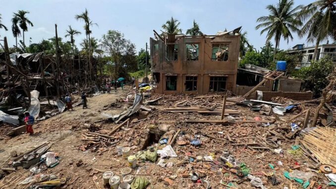 Escola destruída em Thayet Thapin, estado de Rakhine, Mianmar, após ataque aéreo da junta militar, com destroços espalhados e poucas pessoas no local.