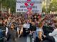 Manifestantes em greve geral na França seguram faixa “MACRON DÉMISSION” e cartazes com mensagens contra a austeridade, ocupando a rua em protesto em 19 de setembro de 2025.
