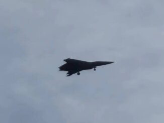 Foto do caça chinês de sexta geração J-50 em voo de teste, com trem de pouso parcialmente recolhido, sob céu nublado.