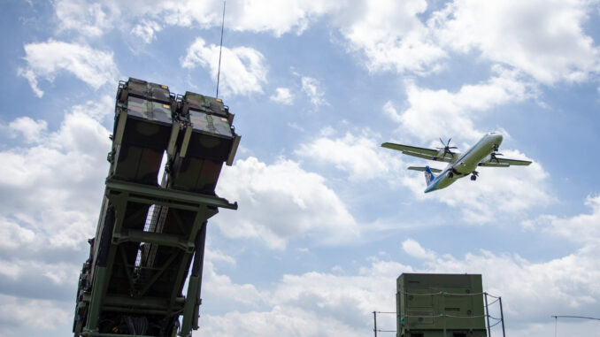 Sistema de defesa aérea taiwanês com mísseis prontos, enquanto avião sobrevoa o céu nublado.