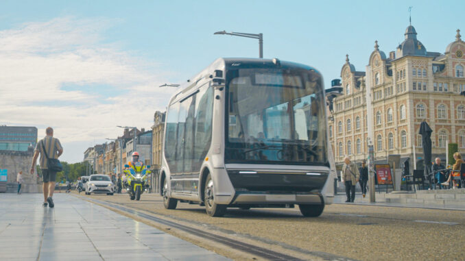 Robobus autônomo da WeRide circulando pelas ruas de Leuven, Bélgica, com pedestres e veículos ao redor.