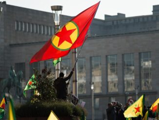 Homem segurando a bandeira do PKK durante um protesto pró-curdo em Bruxelas, Bélgica