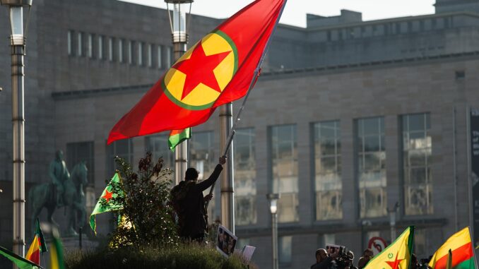 Homem segurando a bandeira do PKK durante um protesto pró-curdo em Bruxelas, Bélgica