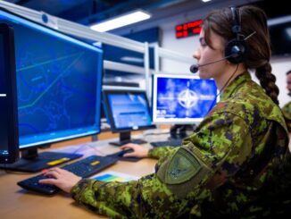 Militar operando sistemas de monitoramento e defesa em estação de comando, com telas mostrando mapas e símbolos da OTAN, representando a vigilância e a cooperação militar na Europa do Norte.