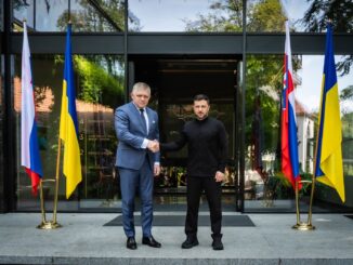 Primeiro-ministro eslovaco Robert Fico cumprimenta o presidente ucraniano Volodymyr Zelensky em encontro oficial, com bandeiras da Eslováquia e Ucrânia ao fundo.