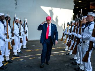 Donald Trump, usando boné vermelho com "USA", saudando tropas dos EUA em formação militar, com fuzis e uniformes brancos.