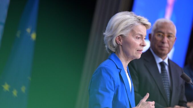 Ursula von der Leyen em pronunciamento, com bandeira da União Europeia ao fundo