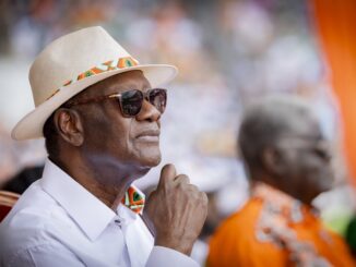 Presidente Alassane Ouattara durante evento público na Costa do Marfim, usando chapéu claro e óculos escuros.
