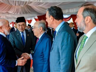 Presidente Lula cumprimenta autoridades durante cerimônia na Malásia, cercado por diplomatas e líderes locais.