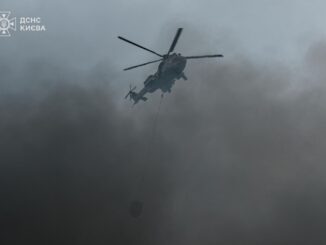 Helicóptero derramando água sobre área urbana em meio à fumaça, enquanto ataques russos atingem Kiev e Dnipropetrovsk.