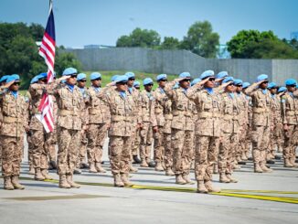 Soldados da Malásia em formação militar, usando uniformes camuflados e boinas azuis, saudando durante cerimônia de 7 de novembro de 2024.
