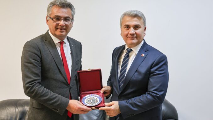 Tufan Erhürman e Dr. Mustafa Canbey segurando um prato comemorativo durante reunião em 26 de fevereiro de 2025.