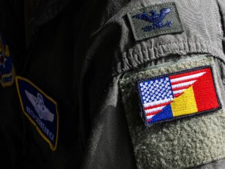Soldado americano usando patch com as bandeiras dos EUA e Romênia no uniforme durante atividade militar em base romena.