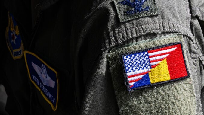Soldado americano usando patch com as bandeiras dos EUA e Romênia no uniforme durante atividade militar em base romena.