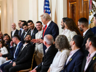 O presidente Donald Trump conversa sorrindo com ex-reféns israelenses libertados durante encontro oficial na Casa Branca, com bandeira dos Estados Unidos ao fundo.