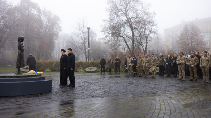 Presidente ucraniano e militares em homenagem às vítimas do Holodomor em Kiev, com velas e flores em meio à neblina
