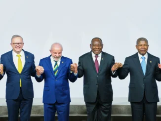 Líderes do G20 posam para foto em summit em Joanesburgo, África do Sul, com bandeiras de vários países ao fundo.