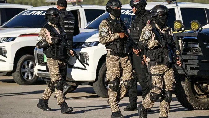 Agentes da polícia venezuelana patrulham pista do Aeroporto Simón Bolívar antes da chegada de voo com migrantes venezuelanos repatriados dos EUA.