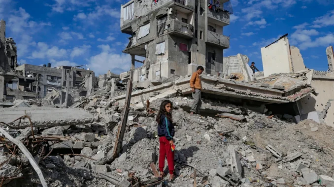 Duas crianças observam prédios destruídos após ataque na Faixa de Gaza.