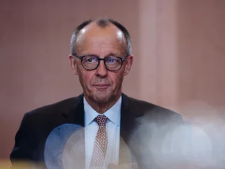 Friedrich Merz em pé, falando ao microfone, durante coletiva sobre segurança europeia — 2025.