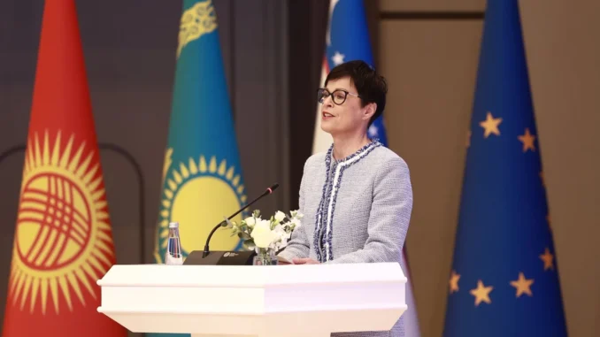 Representante da União Europeia discursa em fórum sobre o Corredor de Transporte Transcaspiano em Tashkent, com bandeiras da UE e de países da Ásia Central ao fundo.